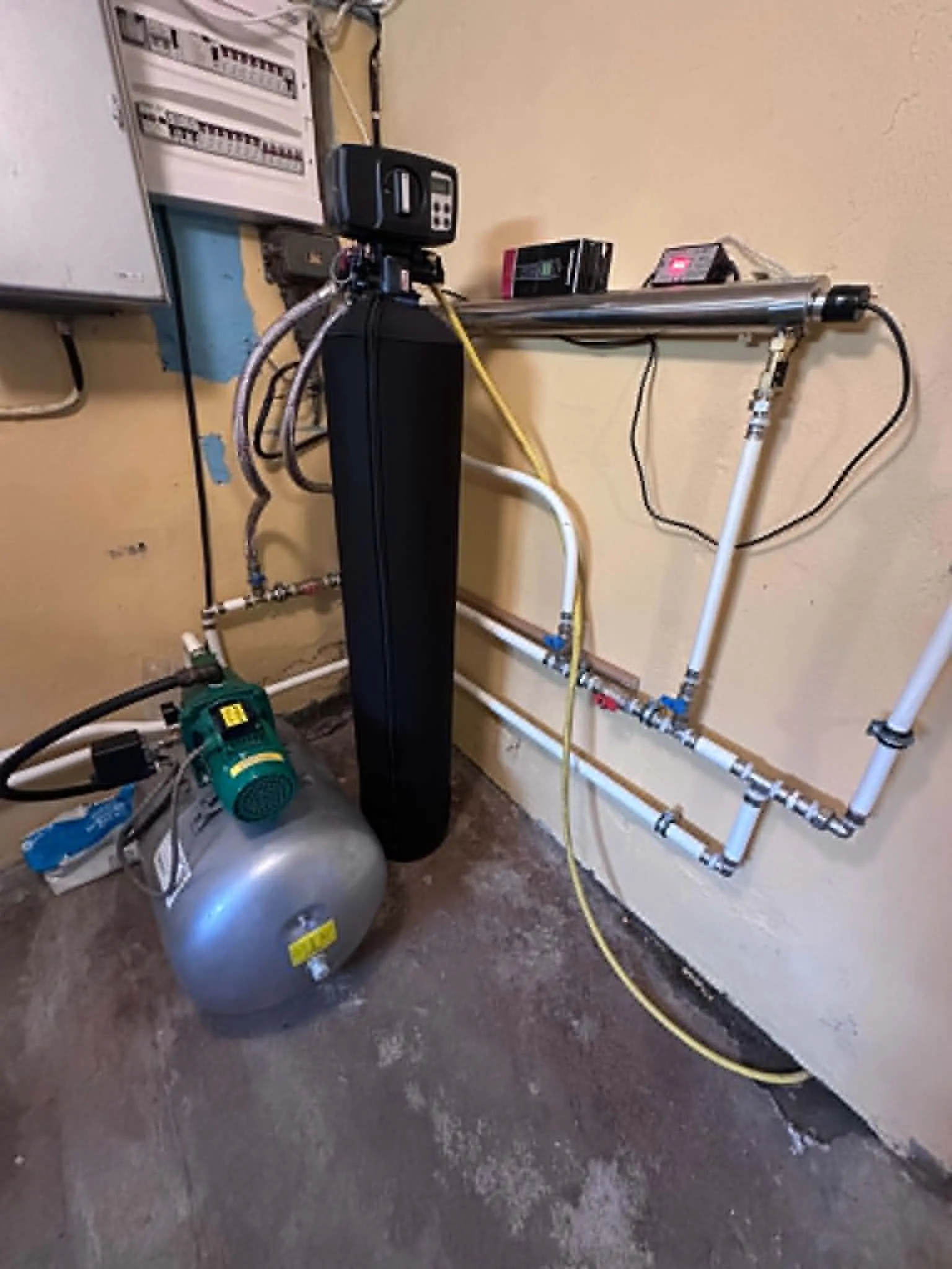 Installerad vattenfilteranläggning med pump och röranslutningar.